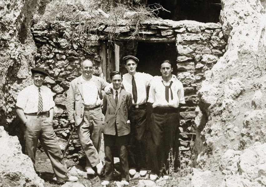 Cinc homes davant de la porta d'una construcció derruïda